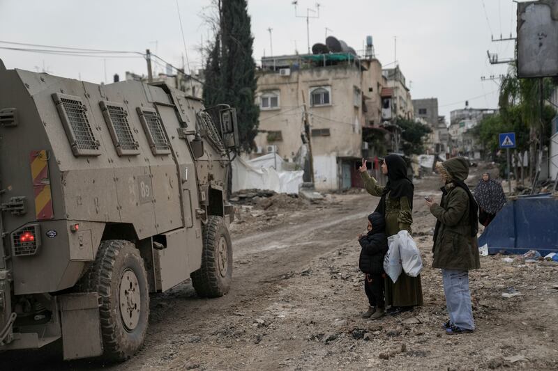 A Palestinian woman flashes a V-sign towards Israeli troops during an army raid in the Tulkarem refugee camp on the West Bank (AP Photo/Nasser Nasser)