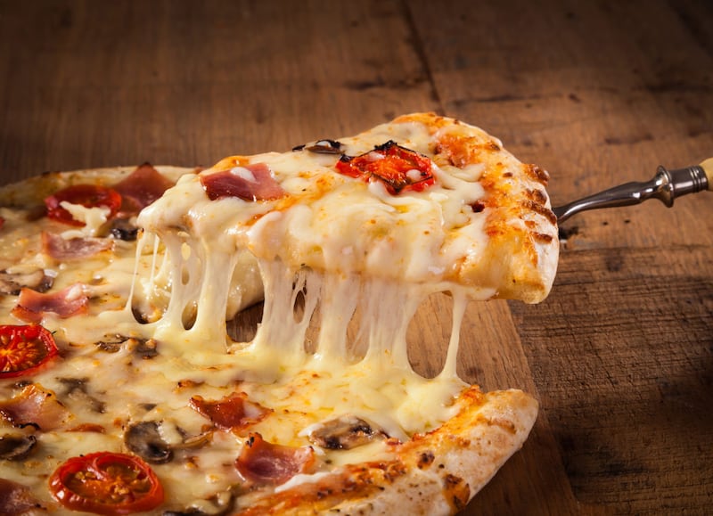 A slice of pizza is pulled from the whole