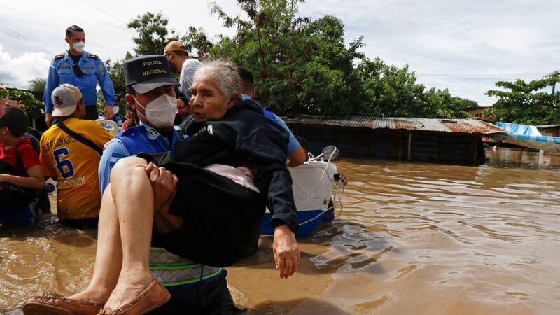 A National Police officer carries an elderly woman out of an area flooded by water brought by Hurricane Eta in Jerusalen, Honduras, on November 5 2020. The storm has claimed 12 lives in Honduras. It&nbsp;hit Nicaragua as a Category 4 hurricane two days before had become more of a vast tropical rainstorm, but it was advancing so slowly and dumping so much rain that much of Central America remained on high alert. Picture by&nbsp;Delmer Martinez, AP Photo