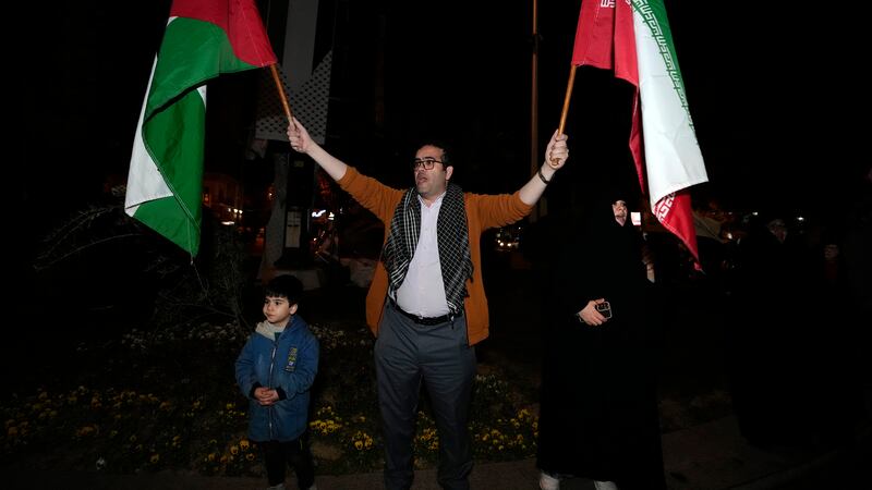 A demonstrator waves Iranian and Palestinian flags during an anti-Israeli gathering at the Felestin (Palestine) Square in Tehran, Iran (Vahid Salemi/AP)