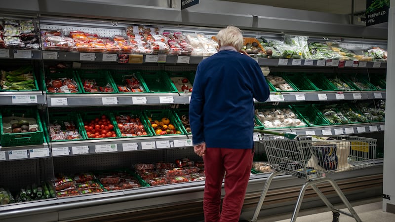 A shopper looks at salad vegetables in a branch of Waitrose