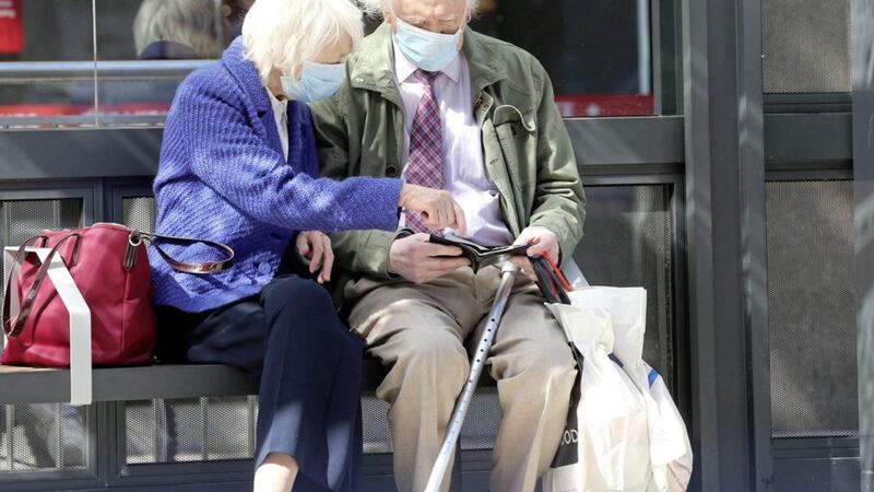 An elderly couple wear face masks at a bus stop in Belfast. Picture by Stephen Davison 