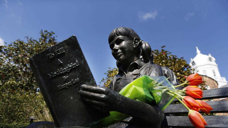 Flowers are placed on a statue of a girl reading Harper Lee's To Kill a Mockingbird, in memorial of Lee in Monroeville, Alabama. Picture by Brynn Anderson, Associated Press