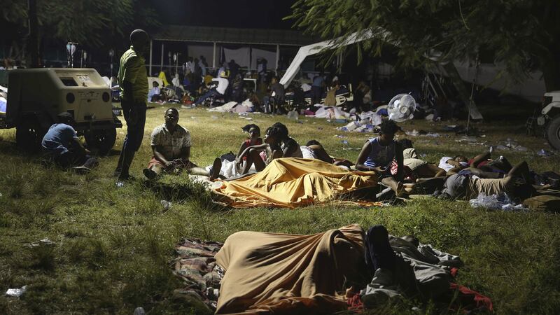 People displaced from their earthquake destroyed homes spend the night outdoors in a grassy area that is part of a hospital in Les Cayes, Haiti, late Saturday, August 14, 2021 (AP Photo/Joseph Odelyn)&nbsp;