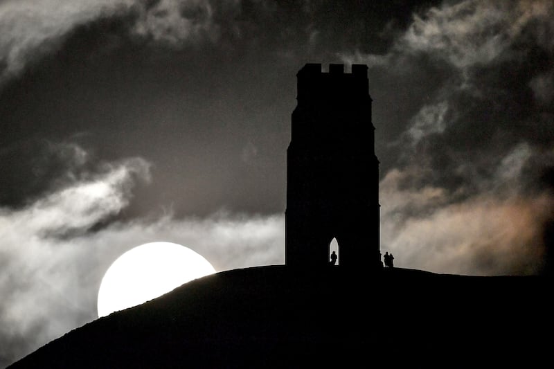 Large white moon rises above the hill Glastonbury Tor sits on