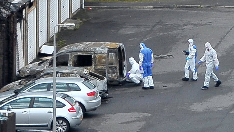 Forensic experts move in to examine a burnt-out Royal Mail van following an explosion at Palace Barracks yesterday 