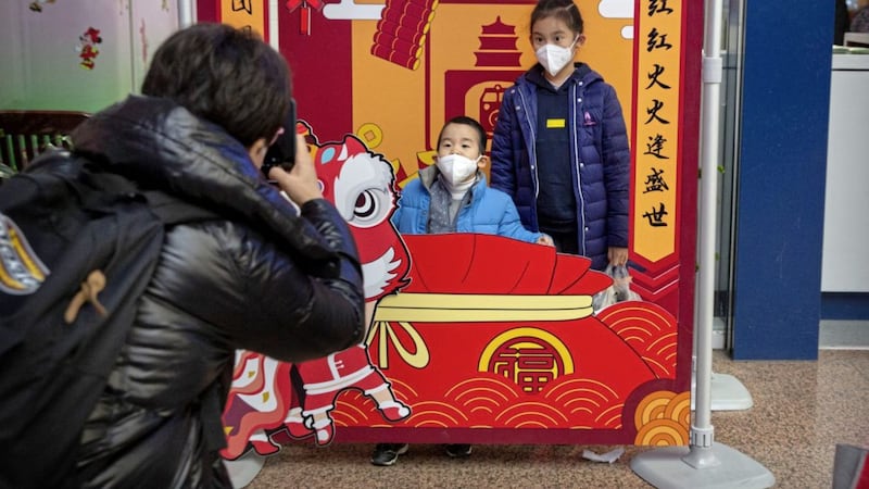 Children wearing face masks pose for photos at a display for the upcoming Lunar New Year, the Year of the Rat, at the Beijing West Railway Station in Beijing. Picture by Mark Schiefelbein/AP 