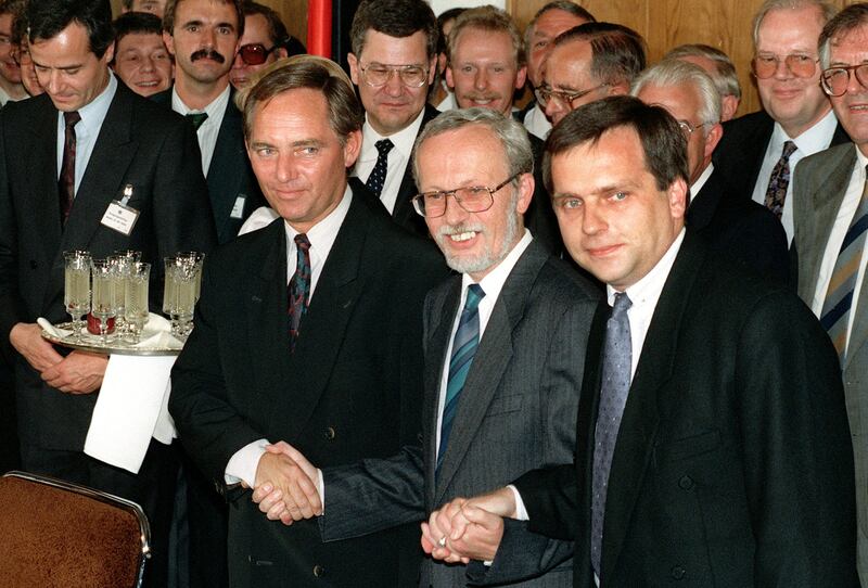 West German secretary of state Wolfgang Schaeuble, left, his East German counterpart Guenther Krause, right, and East German prime minister Lothar de Maizire, centre, symbolically holding hands following the signing of the German unification treaty in East Berlin on August 3 1990 (Hansjoerg Krauss/AP)
