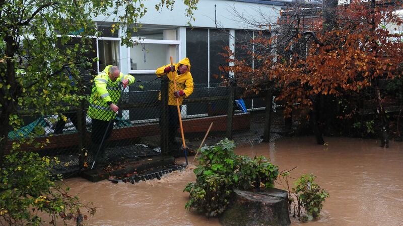Two men work to keep clear a drain in a beck behind the Friarage Hospital in Northallerton, North Yorkshire, during heavy rains