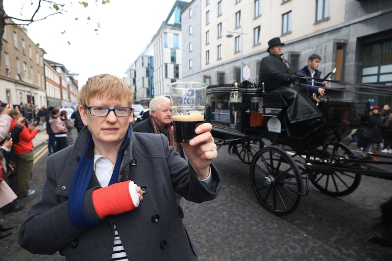 A woman holds up a pint of Guinness on Pearse Street as the funeral procession of Shane MacGowan makes its way through the streets of Dublin ahead of his funeral in Co Tipperary. Picture by Liam McBurney/PA Wire