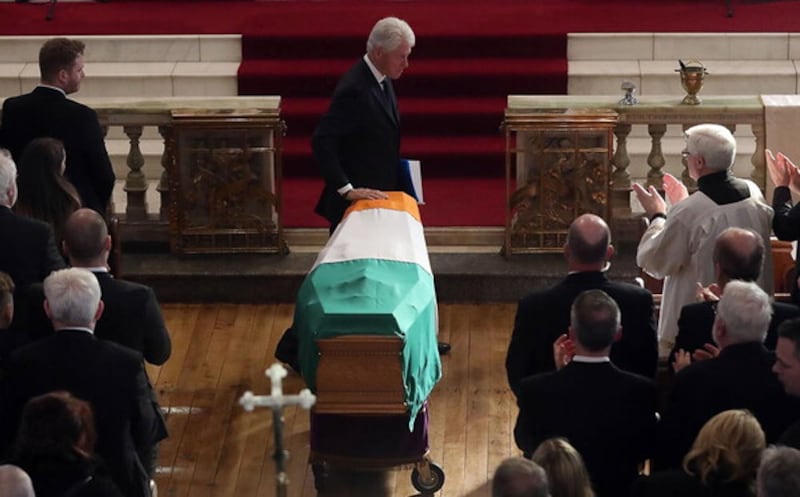Former US President Bill Clinton touches the coffin during the funeral of former deputy first minister Martin McGuinness at St Columba's Church Long Tower, in Derry, Thursday March 23 2017