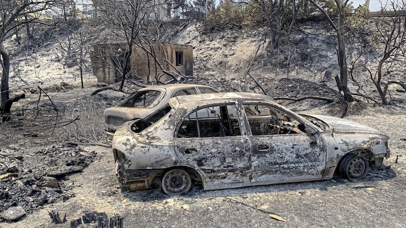 The gutted remains of cars lie on a road after a forest fire on the island of Rhodes, Greece. Some 19,000 people have been evacuated as wildfires continued burning for a sixth day on three fronts 