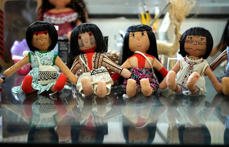 Dolls bearing faces and body paints of different indigenous groups are displayed on a table at a sewing workshop in Rio de Janeiro, Brazil