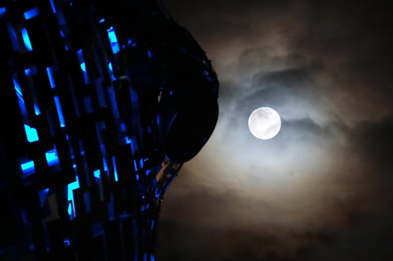 Large bright moon shines down over lit-up Kelpies