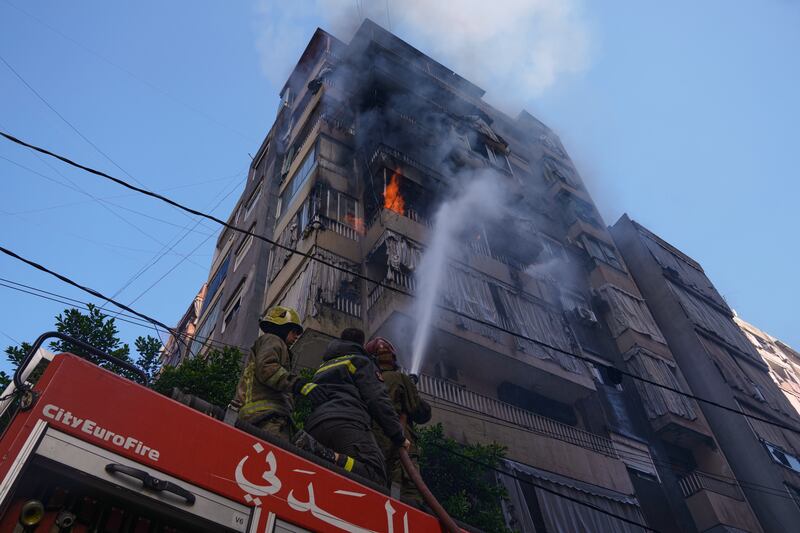 Firefighters spray water on a burning residential building following an Israeli air strike in central Beirut, Lebanon (Bilal Hussein/AP)