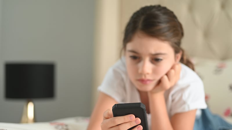 Sad girl (age 10) reading a bullying post on social media. Real people. Copy space