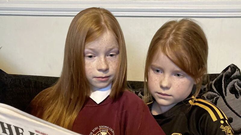 Annie Fox-McGlone, from Carrickmore, pictured left, explains newspapers - and Jake&#39;s column - to her little sister Lois. 