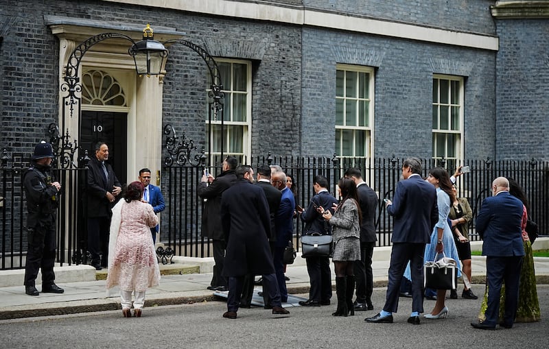 Members of the Muslim community wait to have their picture taken in front of 10 Downing Street’s door as they arrive for an Eid reception