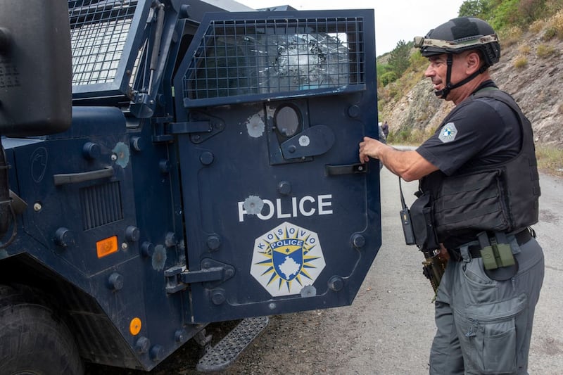 A Kosovo police officer shows the bullet-riddled armoured vehicle near the Banjska monastery