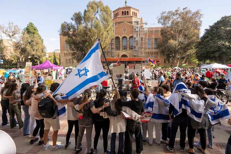 A group of pro-Israel supporters hold arms as they sing and dance outside a pro-Palestinian encampment on the UCLA campus in Los Angeles (Damian Dovarganes/AP)