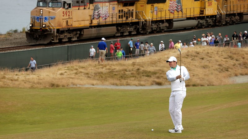 Rory McIlroy prepares to hit from the 16th fairway as a freight train rolls past during the first round of the US Open at Chambers Bay on Thursday<br />Picture: AP