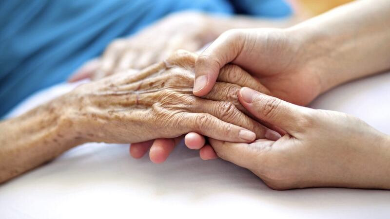 Woman holding senior woman&#39;s hand on bed. 