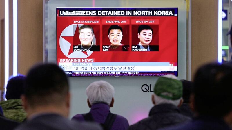 People watch a TV news report showing three Americans, from left, Kim Dong Chul, Tony Kim and Kim Hak Song, detained in the North Korea 