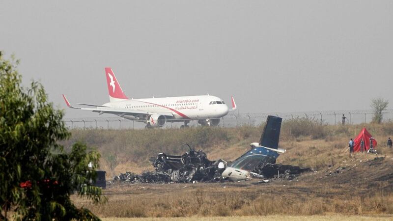 Remains of Bangladesh&#39;s US-Bangla Flight BS211 lies on the ground as a plane takes off from Tribhuvan International Airport in Kathmandu, Nepal, on Tuesday. Picture by Niranjan Shrestha, Associated Press 