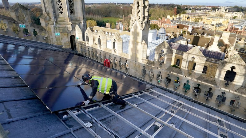 A photovoltaic engineer at work installing solar panels on the roof of the 15th century chapel at King’s College Cambridge (Gareth Fuller/ PA)