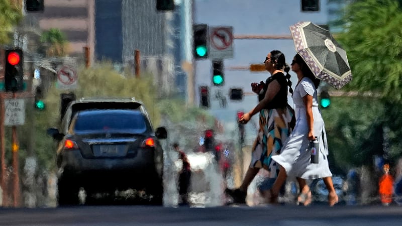 Heat ripples engulf two ladies while crossing the street in central Phoenix, Arizona (Matt York/AP)