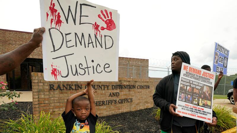 An anti-police brutality activist looks back at the entrance to the Rankin County Sheriff’s Office (Rogelio V Solis/AP)
