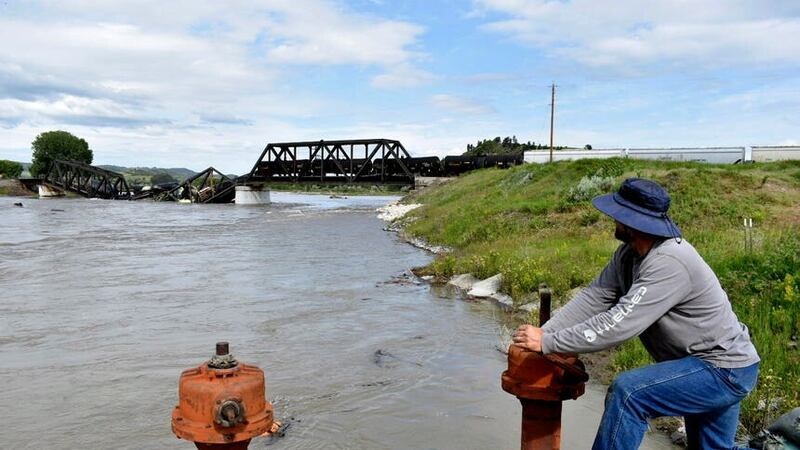 Kelly Hitchcock closes an irrigation ditch just down river from a bridge collapse (Matthew Brown/AP)