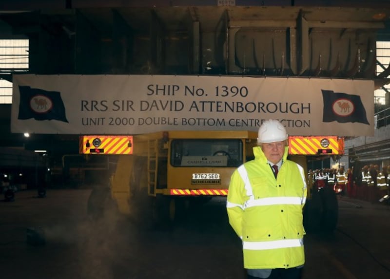Sir David Attenborough stands in front of a section of the keel of the RRS Sir David Attenborough