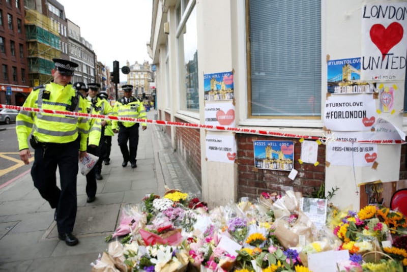 Police walk past flowers near London Bridge