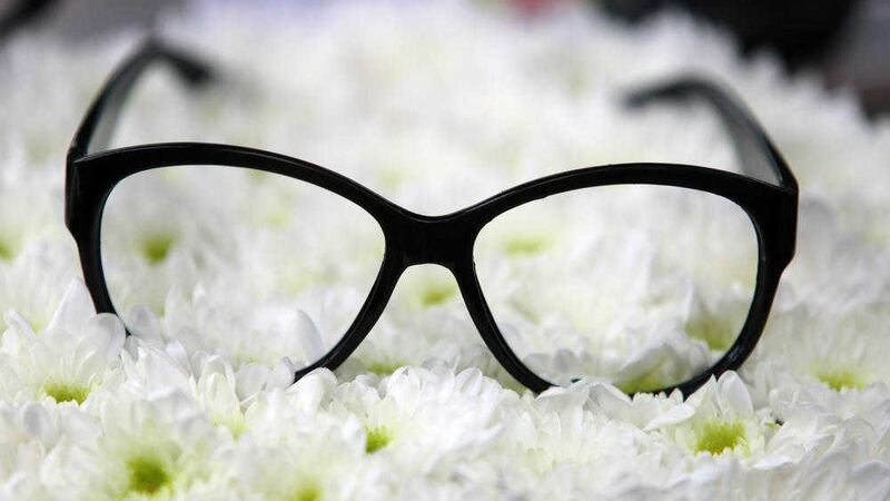 A pair of glasses rest on flowers in a hearse carrying the coffin of Ronnie Corbett in south London