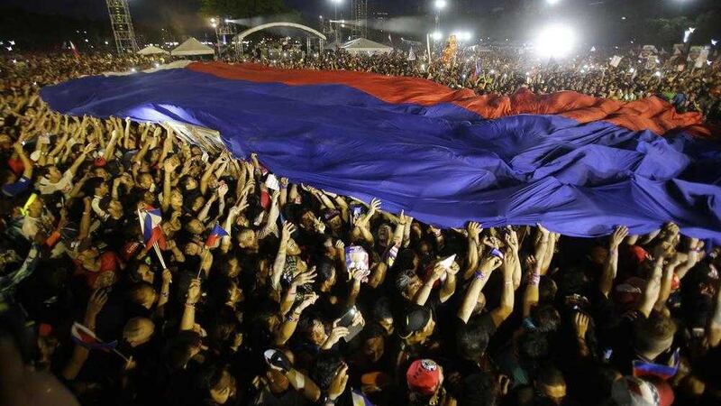 Supporters pass around the Philippine flag during the final campaign rally of Philippine presidential race front-runner Davao city mayor Rodrigo Duterte in Manila, Philippines. Picture by Aaron Favila, Associated Press