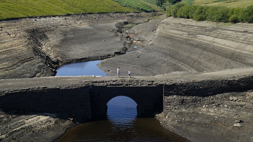People walk across the dry cracked earth at Baitings Reservoir in Ripponden, West Yorkshire (PA)