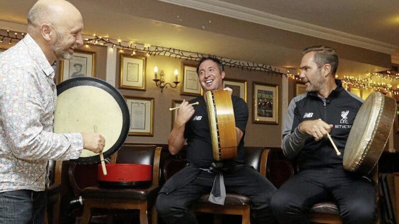 Robbie Fowler (centre) and Jason McAteer (right) are shown how to play the bodhr&aacute;n by Brian Fleming from the Irish House Party. Picture from Liverpool FC 