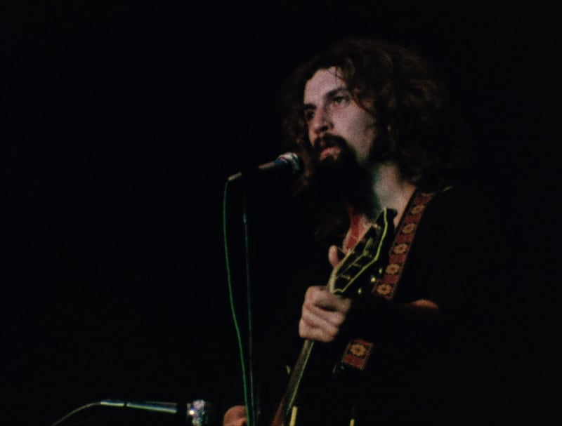 A still showing Billy Connolly playing his guitar onstage taken from the film Big Banana Feet
