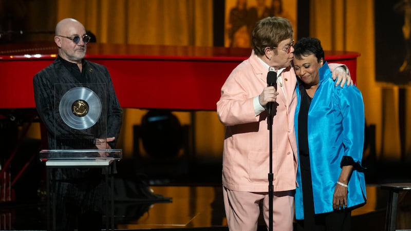 The singer, centre, collected the award together with his songwriting partner Bernie Taupin, left (Kevin Wolf/AP)