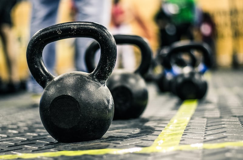 W8HXAJ Different sizes of kettlebells weights lying on gym floor. Equipment commonly used for crossfit training at fitness club.