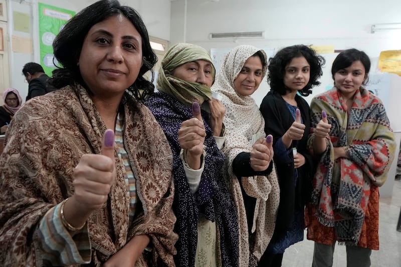 Women show their marked thumbs after casting their vote at a polling station during the country’s parliamentary elections in Karachi, Pakistan (Fareed Khan/AP)