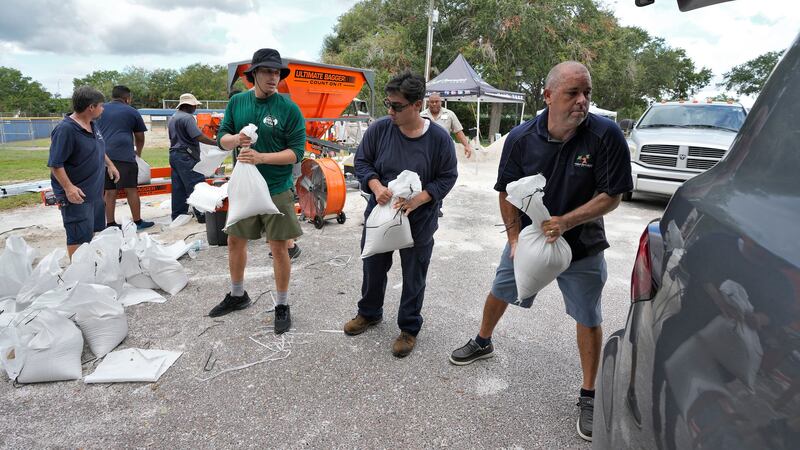 Members of the Tampa, Fla., Parks and Recreation Dept., help residents load sandbags Monday, Aug. 28, 2023, in Tampa, Fla. Residents along Florida’s gulf coast are making preparations for the effects of Tropical Storm Idalia. (AP Photo/Chris O’Meara)