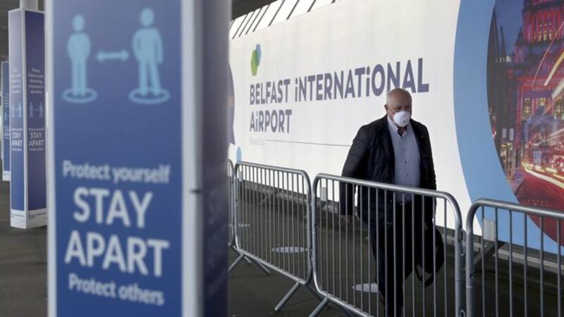 A passenger arrives at Belfast International Airport this morning for the first domestic flight to leave the airport since it was shut down after Coronavirus restrictions were put in place. All passengers entering and flying from the terminal must wear a face mask. Picture by Hugh Russell.