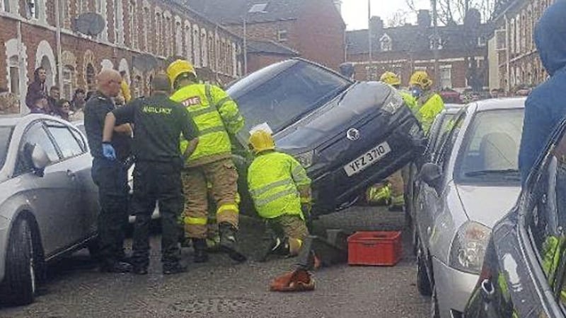 Emergency workers attempting to free a car which got stuck in Belfast's Holyland area yesterday
