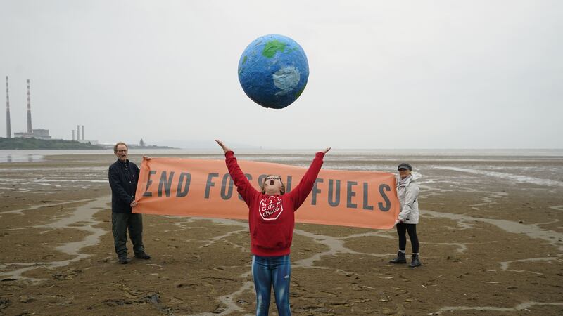Chloe Coghlan, 12, with a model of planet Earth, joins civil society and climate action groups on Sandymount Strand in Dublin (Niall Carson/PA)