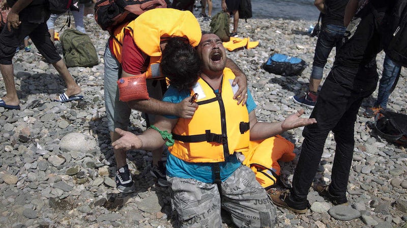 Syrian refugees react as they arrive after crossing aboard a dinghy from Turkey, on the island of Lesbos, Greece, Monday, Sept. 7, 2015. The island of some 100,000 residents has been transformed by the sudden new population of some 20,000 refugees and migrants, mostly from Syria, Iraq and Afghanistan. (AP Photo/Petros Giannakouris) 