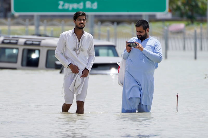 Two men walk through floodwater in Dubai (Jon Gambrell/AP)