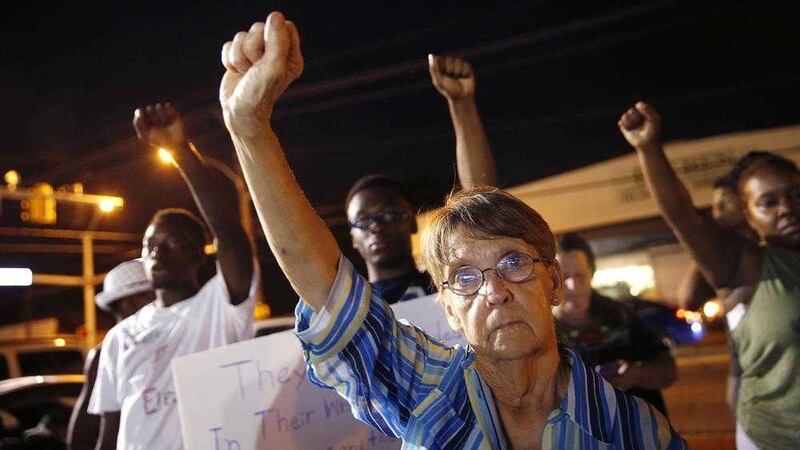 Jackie Silva, of Manvel, Texas, puts her fist up during live music at a night rally in honor of Alton Sterling, outside the Triple S Food mart in Baton Rouge, La.Mr Sterling was shot and killed last Tuesday by Baton Rouge police while selling CD&#39;s outside the convenience store PICTURE: Gerald Herbert/AP 