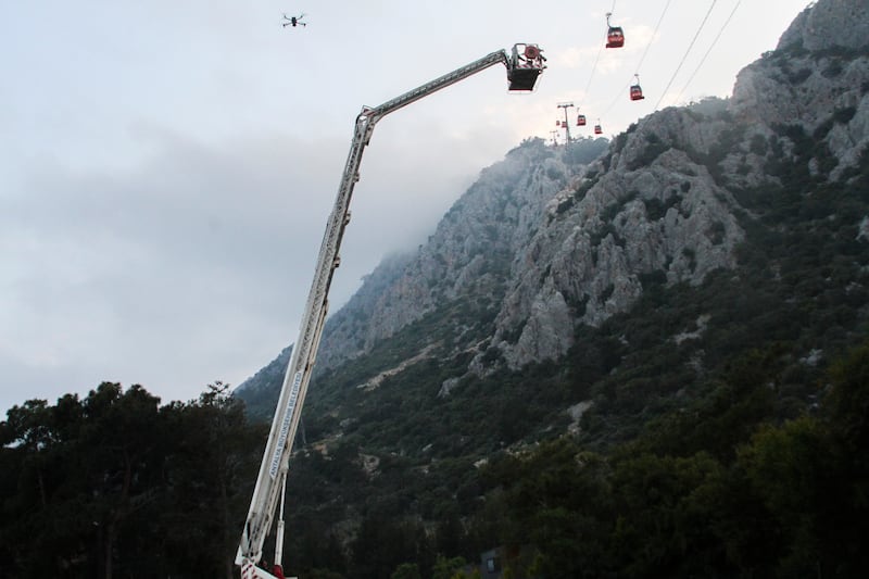 A rescue team work with passengers of a cable car transportation systems outside Antalya (IHA via AP)